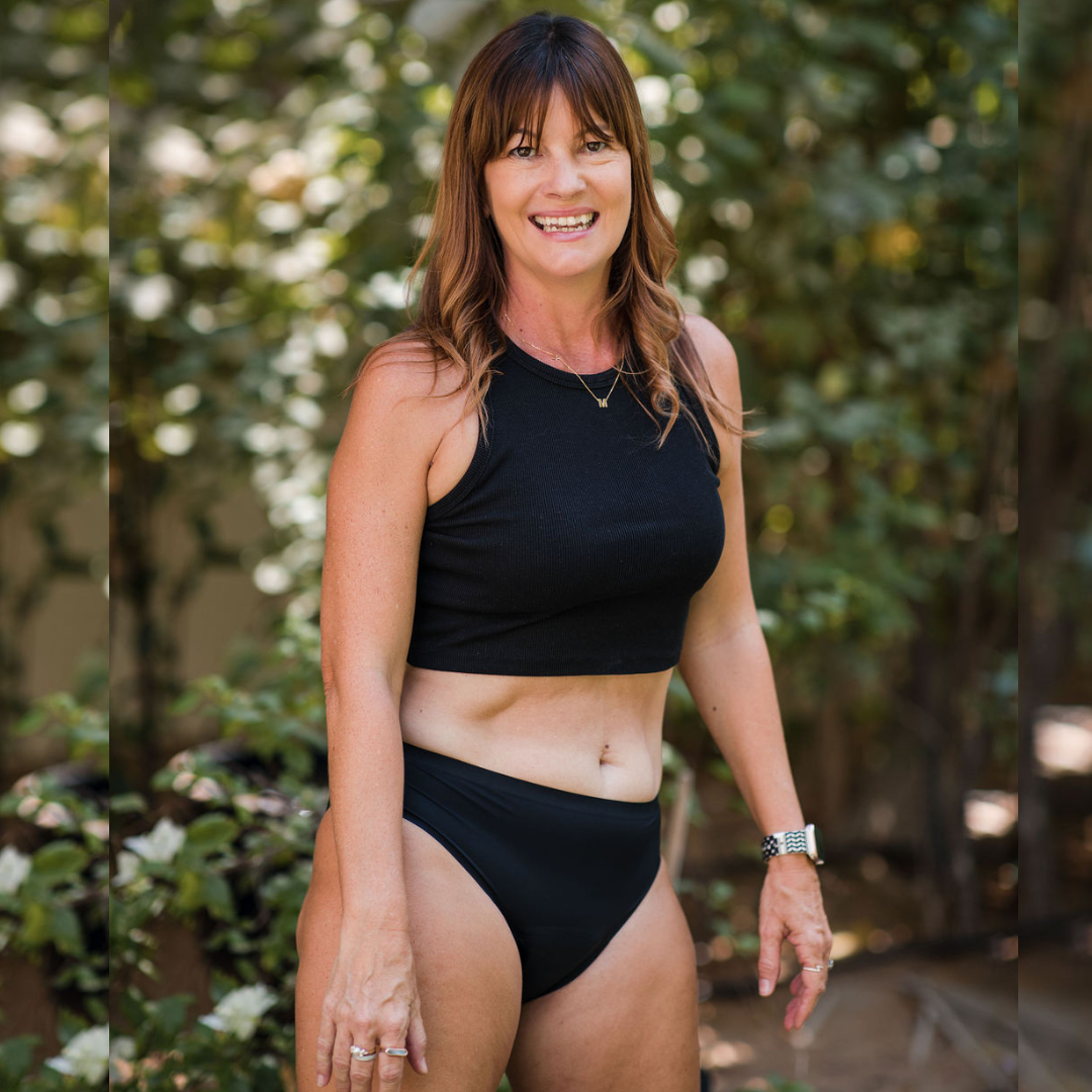 Sahara period underwear. Female wearing Sahara period panties lying on a bed reading a book. Model is wearing black top.