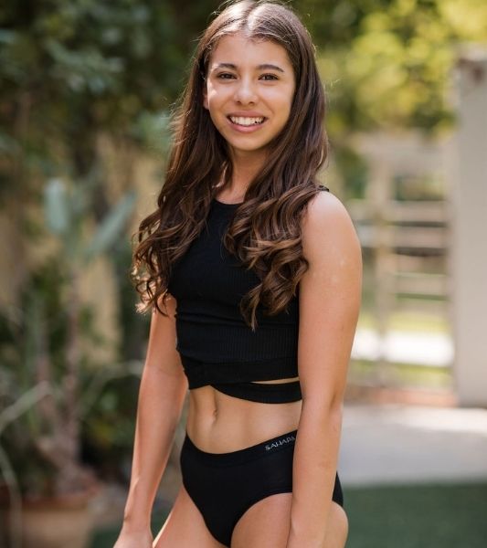 Teen wearing a black sports top and Sahara teen period pants outdoors