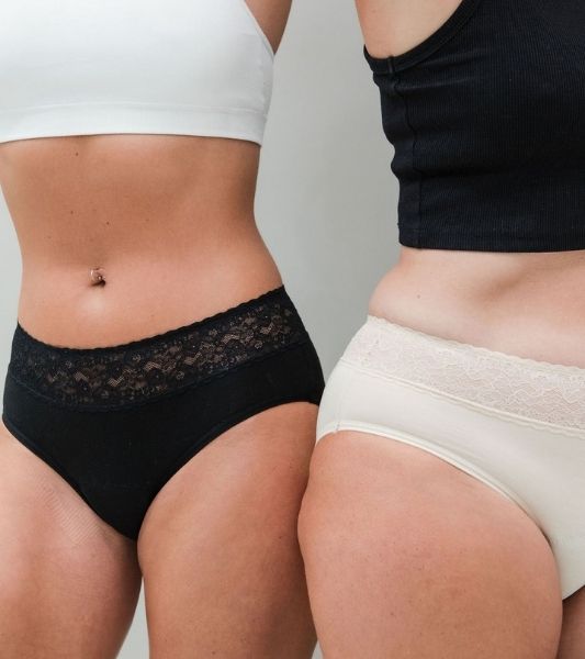 Two women wearing Sahara black lace period pants and beige lace period pants. 